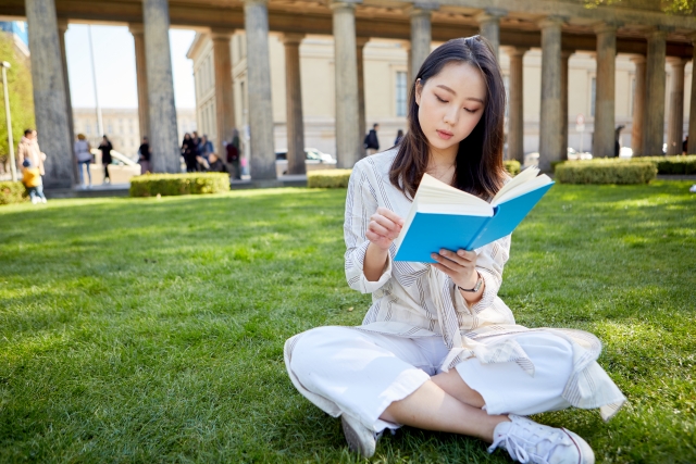 芝生の上で読書する留学生